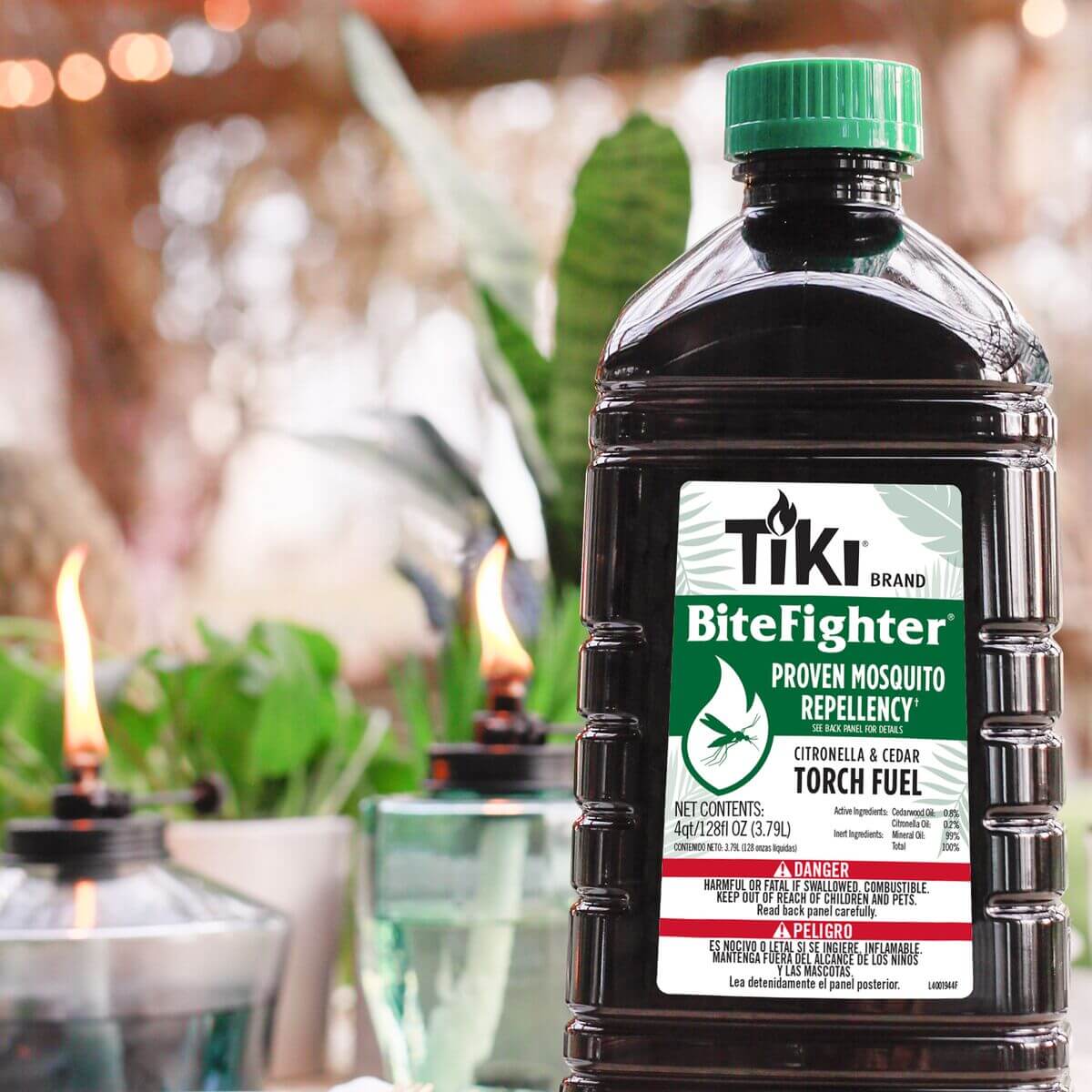 TIKI BiteFighter torch fuel bottle with citronella and cedar, proven mosquito repellency, outdoors with lit torches.