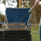 Gold mesh grill basket on black portable grill with folding handle.
