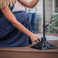 Woman secures a TIKI torch pole into a decorative metal base on a wooden deck, ensuring outdoor torch stability.