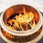 Close-up of a TIKI® fire pit with bright flames and wood pellets burning inside a stainless steel bowl.