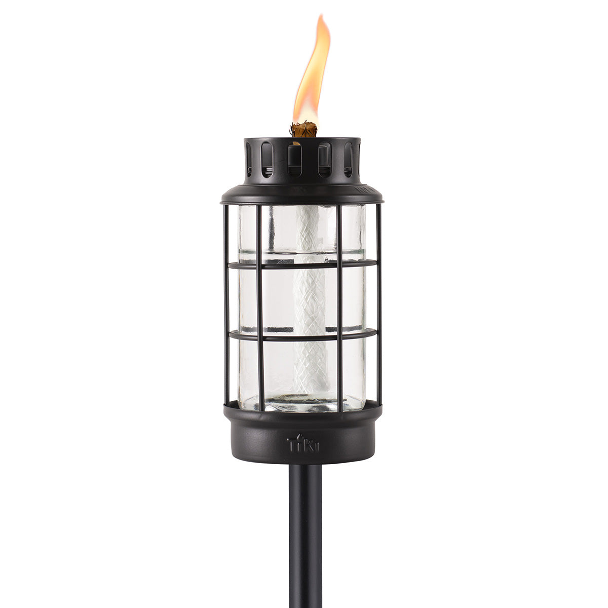 Black metal and glass TIKI® Brand torch with a visible flame, designed for outdoor lighting and ambiance.