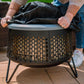 Person placing a weatherproof cover on a TIKI fire pit outdoors; easy protection for patio use.