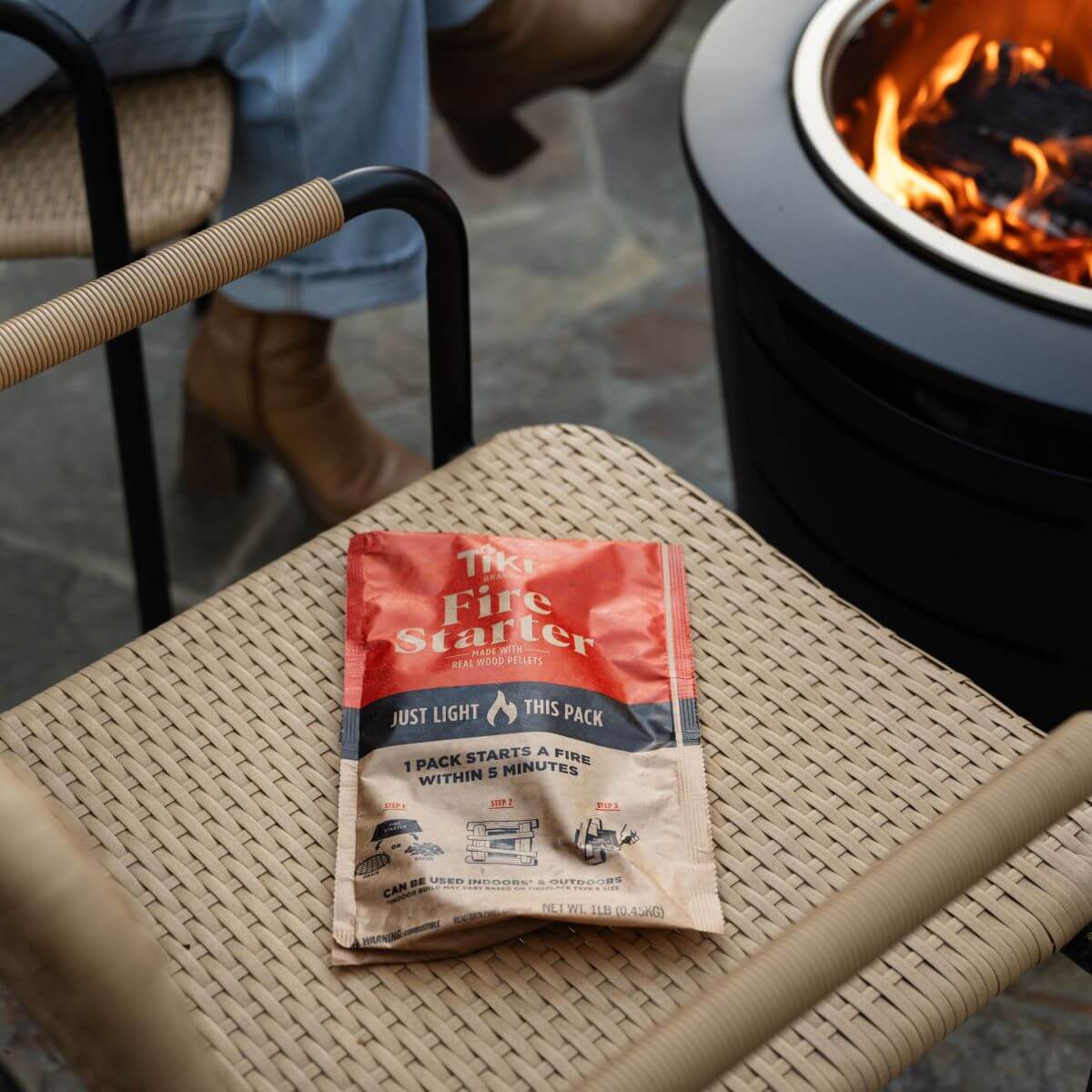 TIKI Fire Starter pack on a woven chair near a fire pit; easy fire starting for indoor or outdoor use.