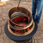 Bronze fire pit with glowing embers, black base, and mesh screen.