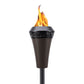 Black metal TIKI torch with decorative top, burning bright flame; outdoor patio lighting product on white background.