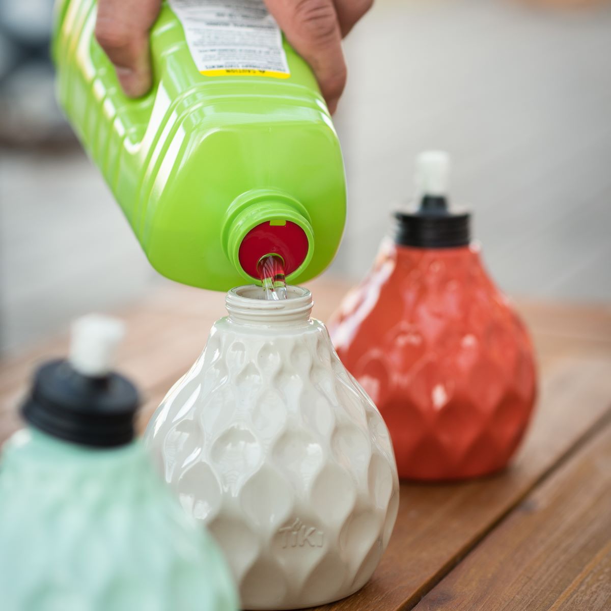 Green bottle pouring liquid into white textured container.