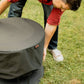 TIKI Brand Patio Smokeless Fire Pit Replacement Cover, person placing cover on fire pit outdoors