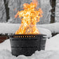 TIKI fire pit burning brightly outdoors in snowy winter setting; black metal design stands out against white snow.