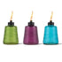 Three textured glass TIKI® table torches in green, purple, and blue, each lit with a visible flame.