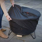 Person covering a TIKI® fire pit with a black weather-resistant cover on a stone patio.