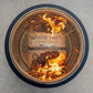 Black fire pit with mesh cover, burning wood inside.