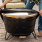 Black outdoor fire pit with gold lid and protective cover being placed on top.