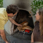 A person places firewood in an outdoor fireplace with TIKI® Fire Starter on the grate, preparing for a safe, easy fire.