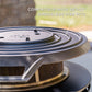 Close-up of a TIKI fire pit accessory lid, compatible with 16–21 inch smokeless fire pits, outdoors.