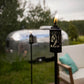 Lit TIKI Brand torches with deer design on a patio, near a camper and outdoor seating. Accessible outdoor ambiance.