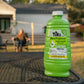 TIKI BiteFighter Clean Burn Torch Fuel bottle on outdoor table; house and person in background. Mosquito repellent.
